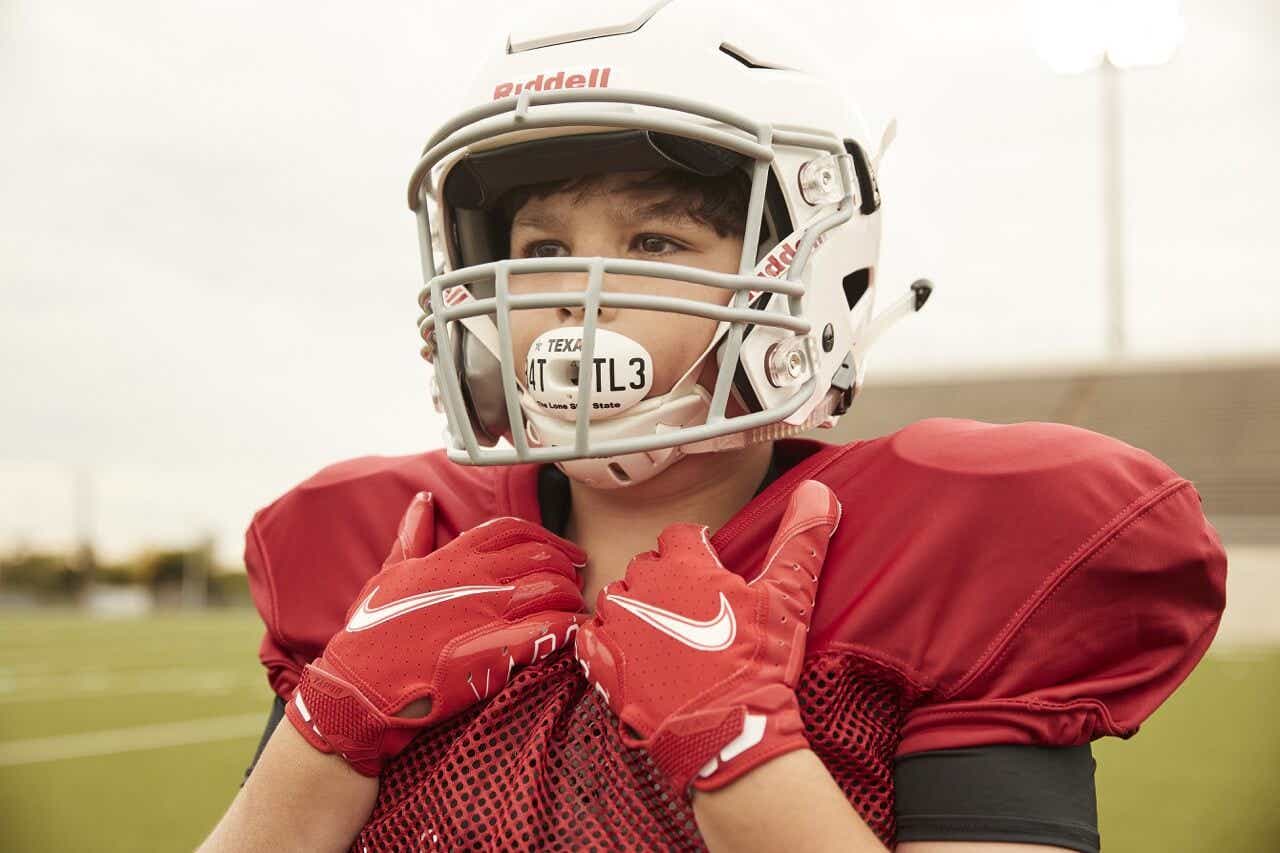 Kid wearing a football helmet and chin straps