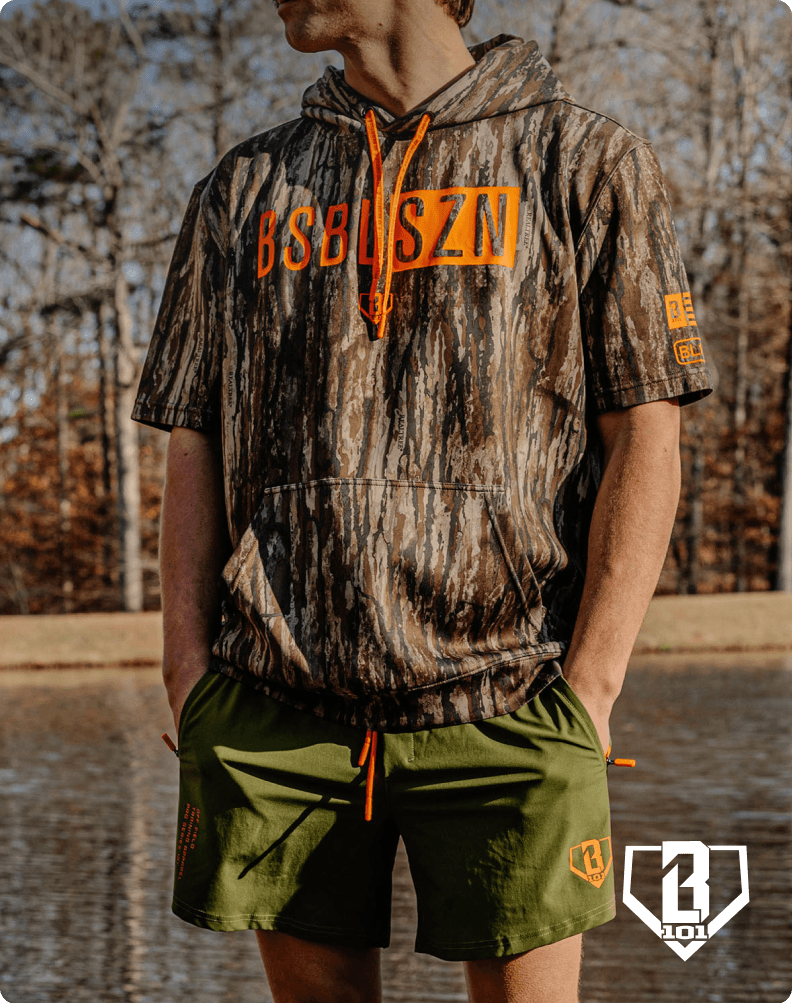 Person wearing a Realtree camo shirt and green shorts standing outdoors with overlaid Baseball Lifestyle 101 logo.