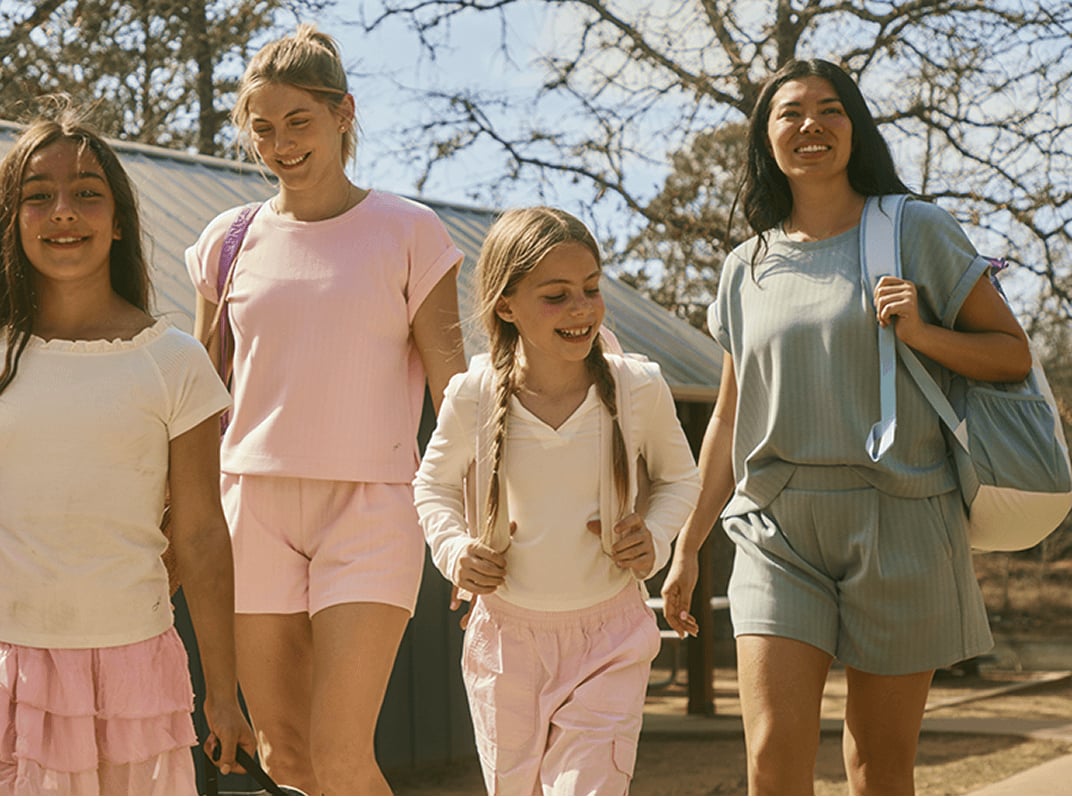 Family walking together outdoors on a warm day, wearing casual spring outfits from Freely.