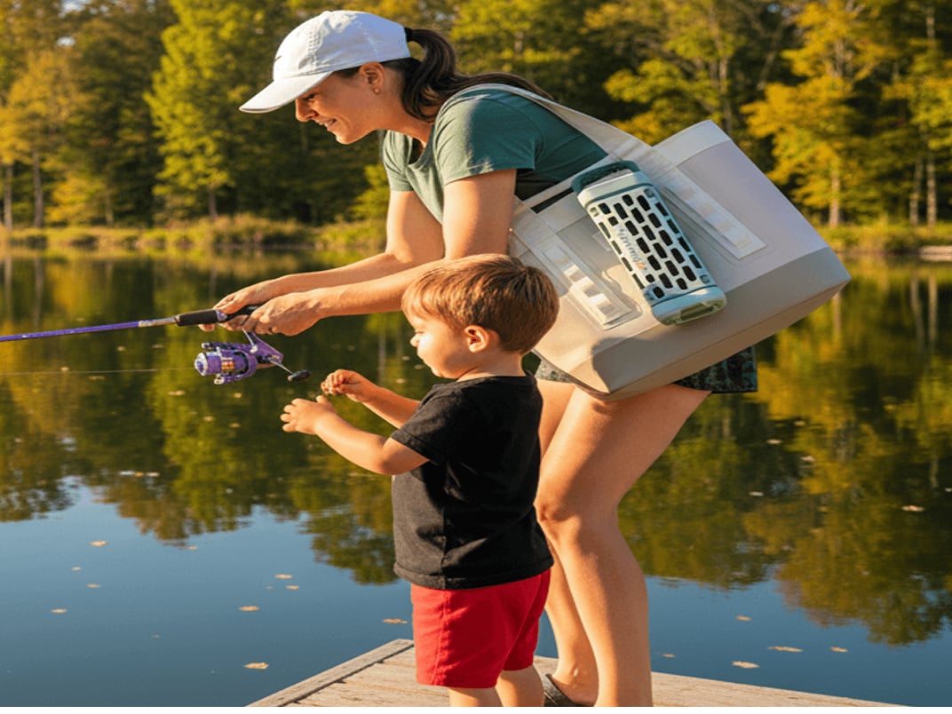 Adult and child fishing together at a calm lake surrounded by trees on a sunny day with a YETI tote and Turtlebox speaker.