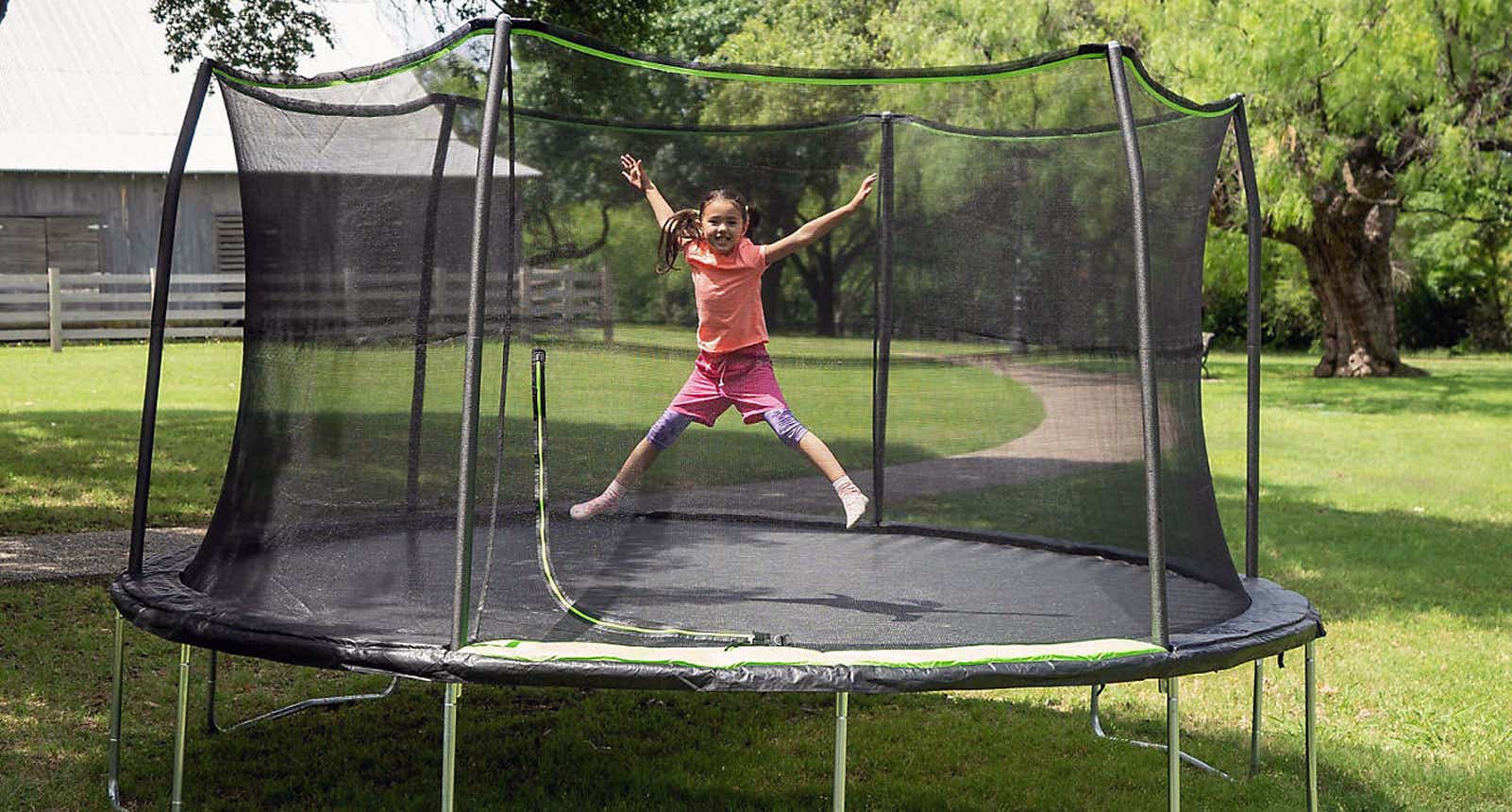 Girl jumping in an outdoor trampoline with safety netting