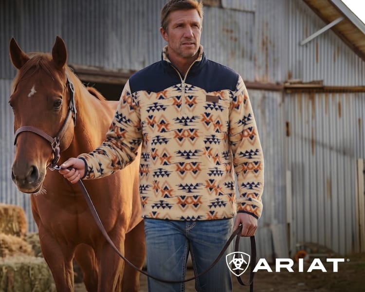 Person standing beside a horse while wearing a patterned western pullover.