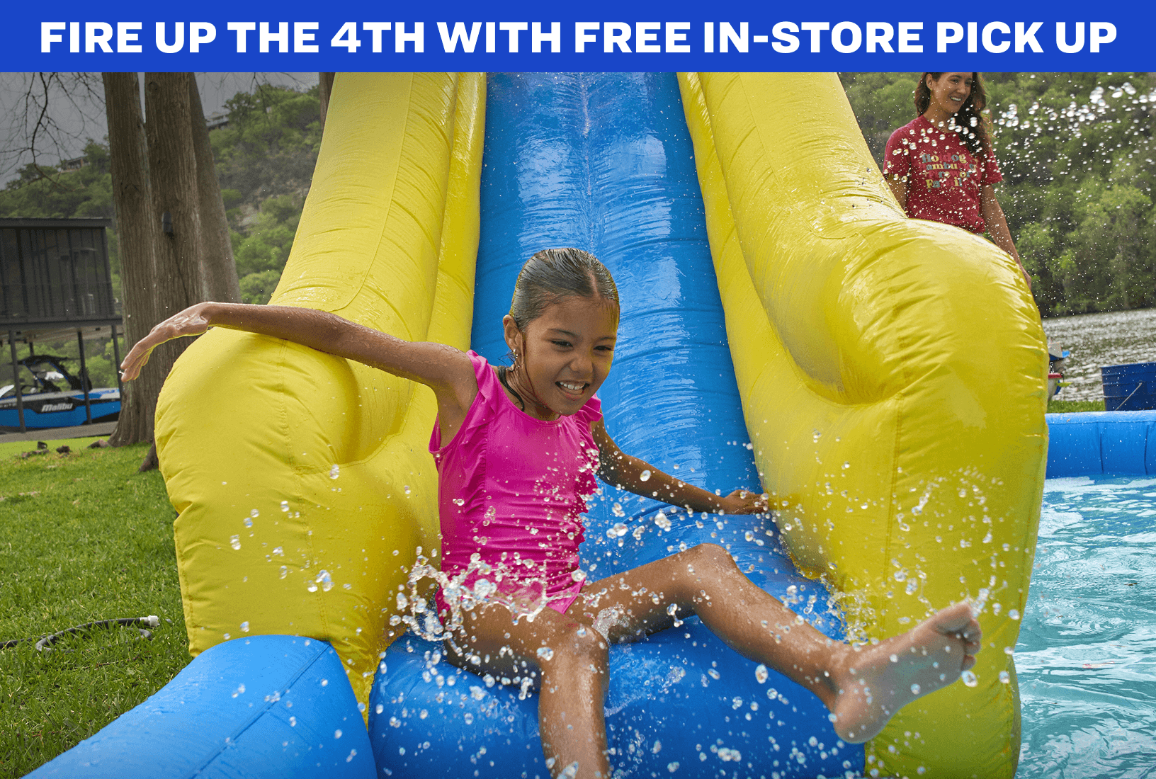 Child sliding down bright yellow inflatable water slide outdoors with water splashing.