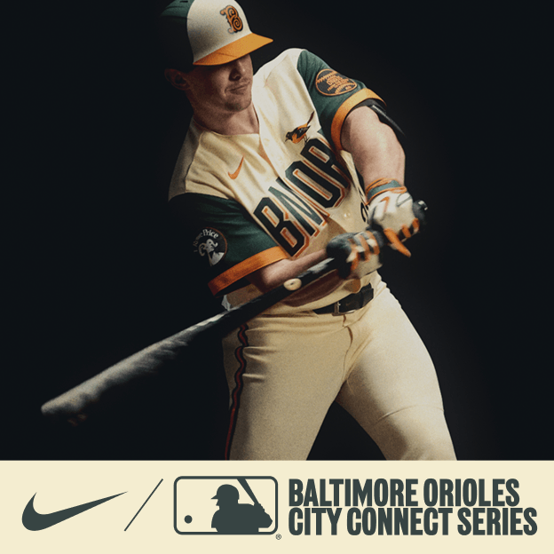 Professional baseball player wearing a cream Baltimore Orioles City Connect jersey and cap, holding a bat in dramatic studio lighting.