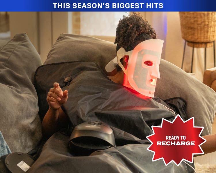 LED red light therapy face mask illuminated with red light while worn during a wellness treatment session with overlaid badge "Ready to Recharge"