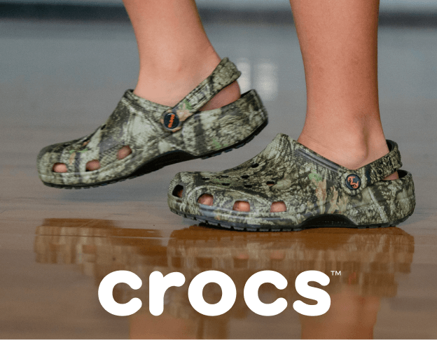 Close-up of Crocs clogs worn with shorts in an indoor gym. Crocs