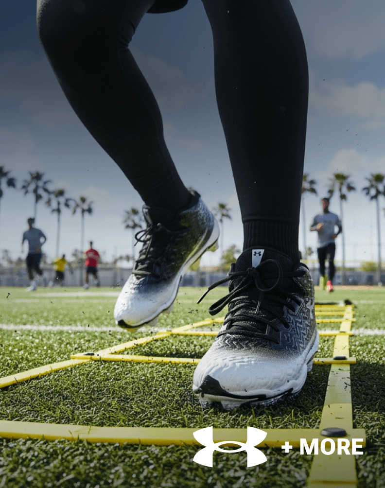 Close-up of Under Armour football cleats worn on an outdoor football field.