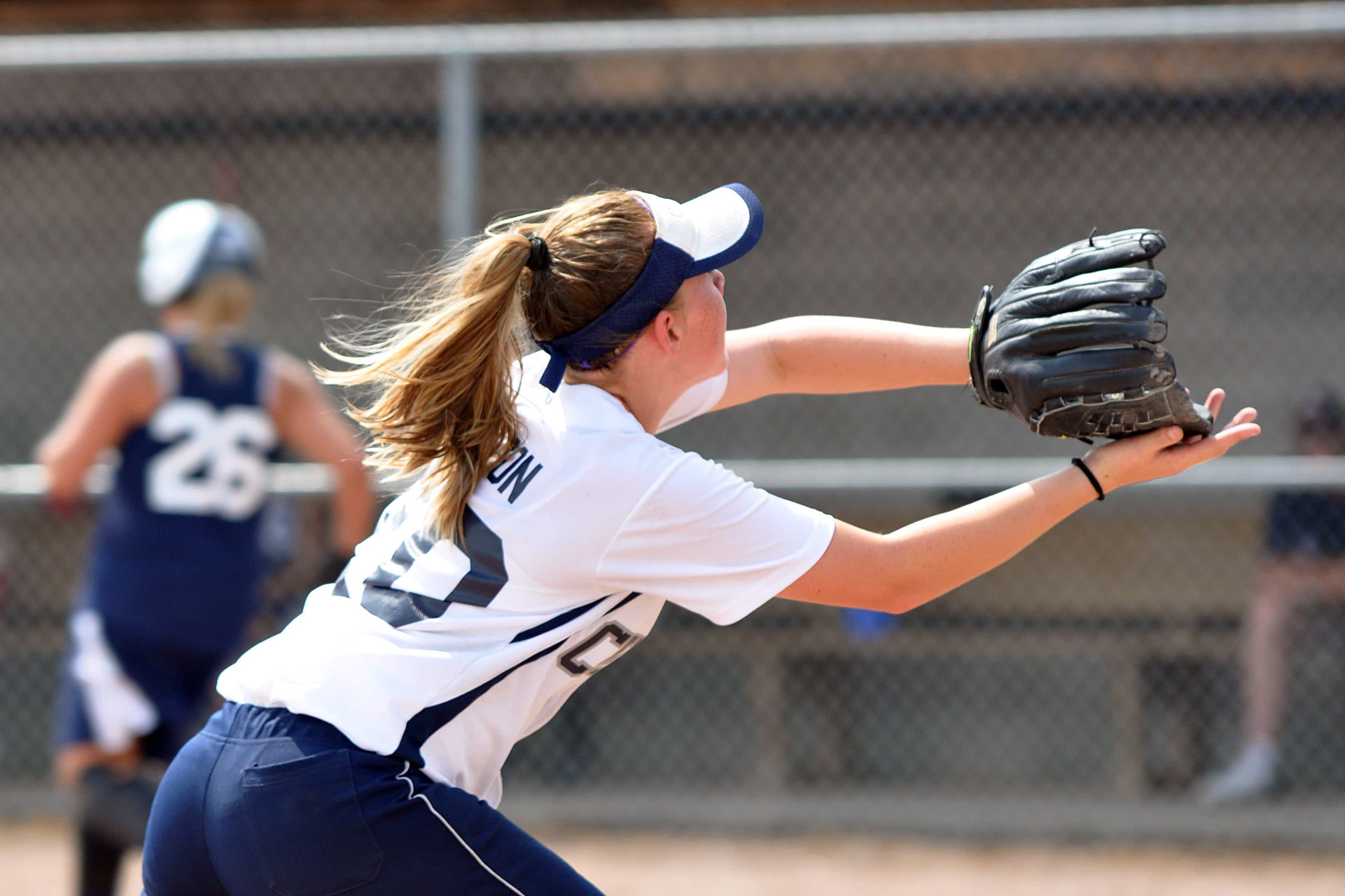 Softball player catching a softball in her glove at a game