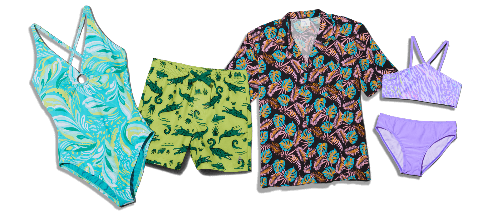 Flat lay of bright summer swim apparel including a turquoise swirl-pattern one-piece swimsuit, a colorful short-sleeve button-up shirt, and green swim trunks with an animal print.
