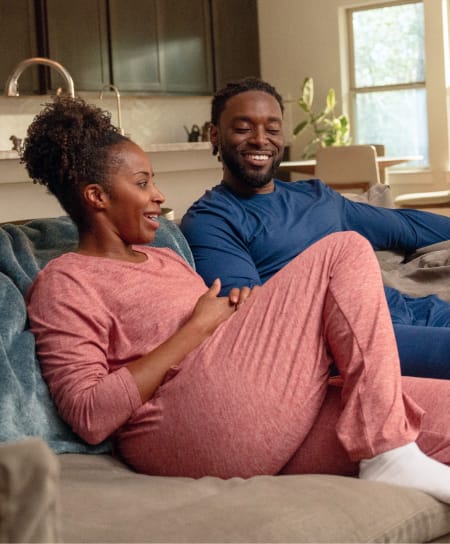 wo people relaxing on a living room couch wearing matching loungewear.