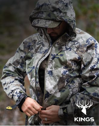 Person wearing camouflage hunting apparel adjusting a camo jacket.