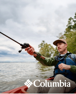 Person kayaking on a calm body of water while fishing, wearing outdoor gear and a life vest, with another kayaker in the background. Columbia logo in the corner.