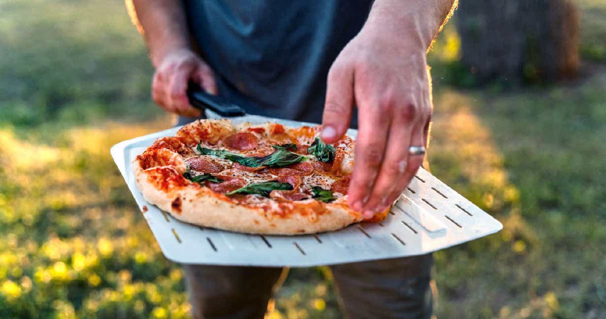 Man serving a freshly baked margherita pizza