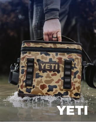 YETI soft cooler in wetlands camouflage pattern carried through shallow water.