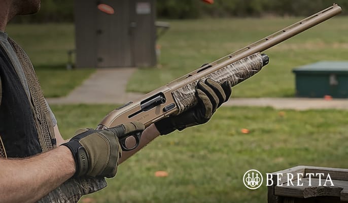 Close-up of a person holding a camouflage Beretta A300 Ultima shotgun outdoors at a shooting range, featuring an Only at Academy badge and Beretta logo.