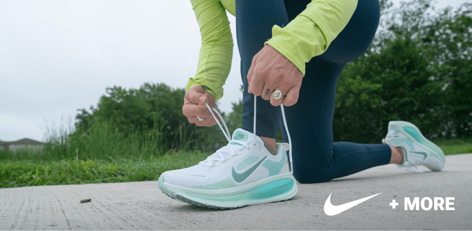 Close-up of person tying Nike running shoe on outdoor path.