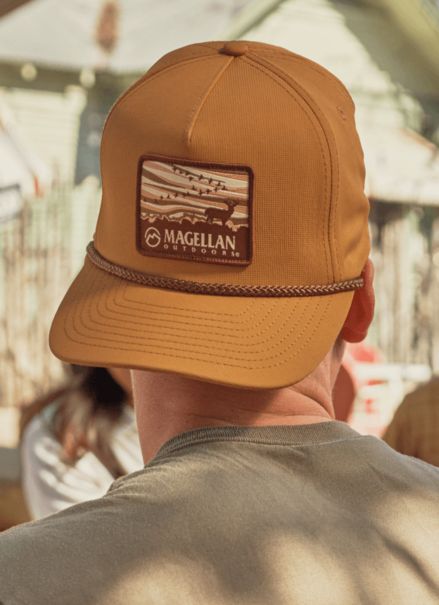 Back view of a person wearing a brown Magellan Outdoors cap outdoors.
