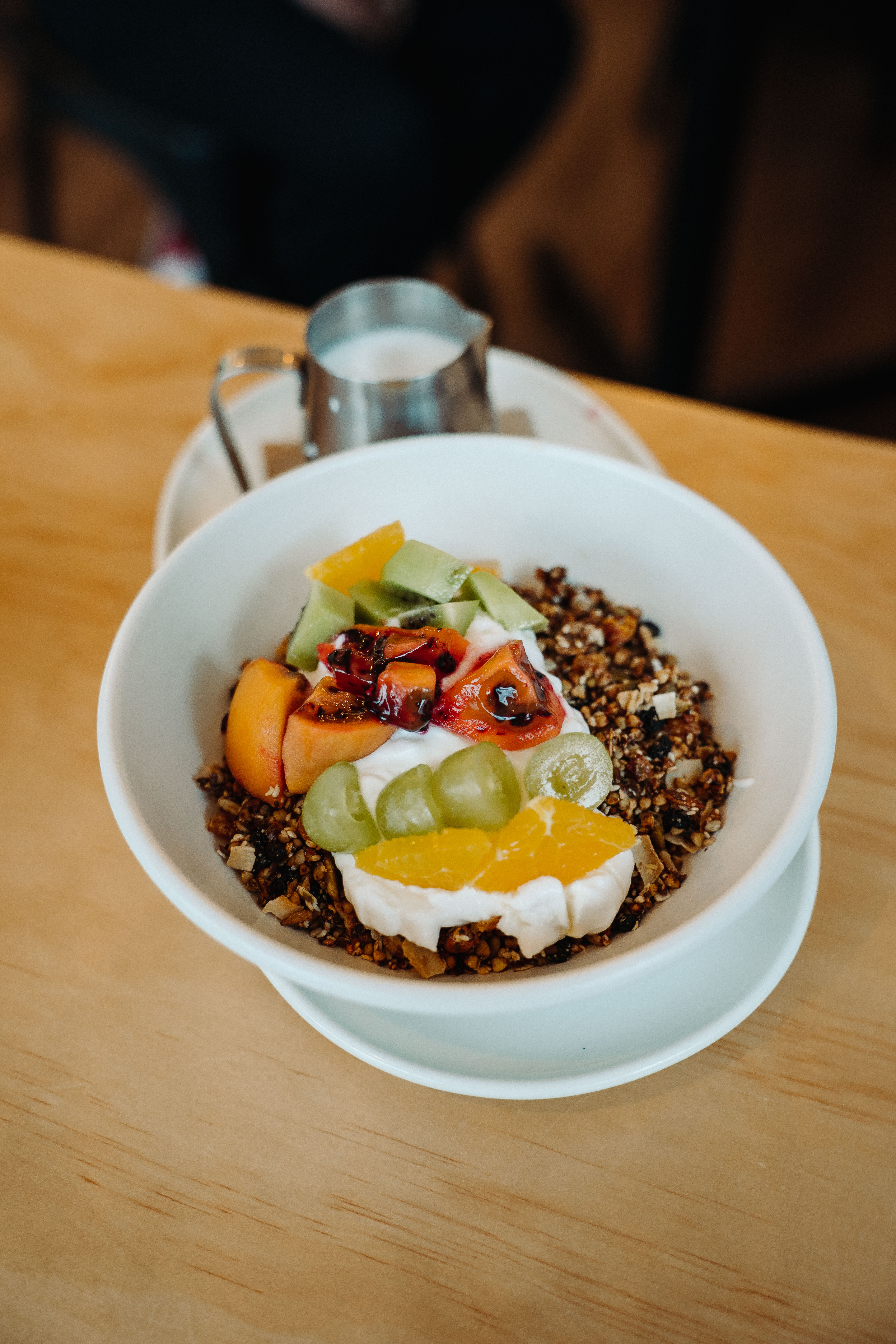 A bright, candid café interior in Christchurch with customers seated at tables and warm natural light. The scene highlights a relaxed, social atmosphere with coffee, food, and modern décor.