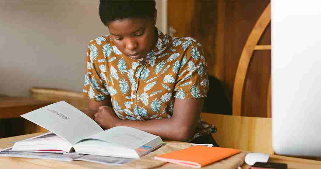 Young woman reading a book studying for college