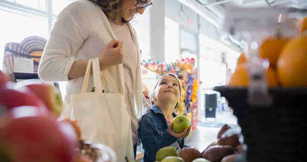 Mother and daughter  looking at fruit while shopping for groceries.