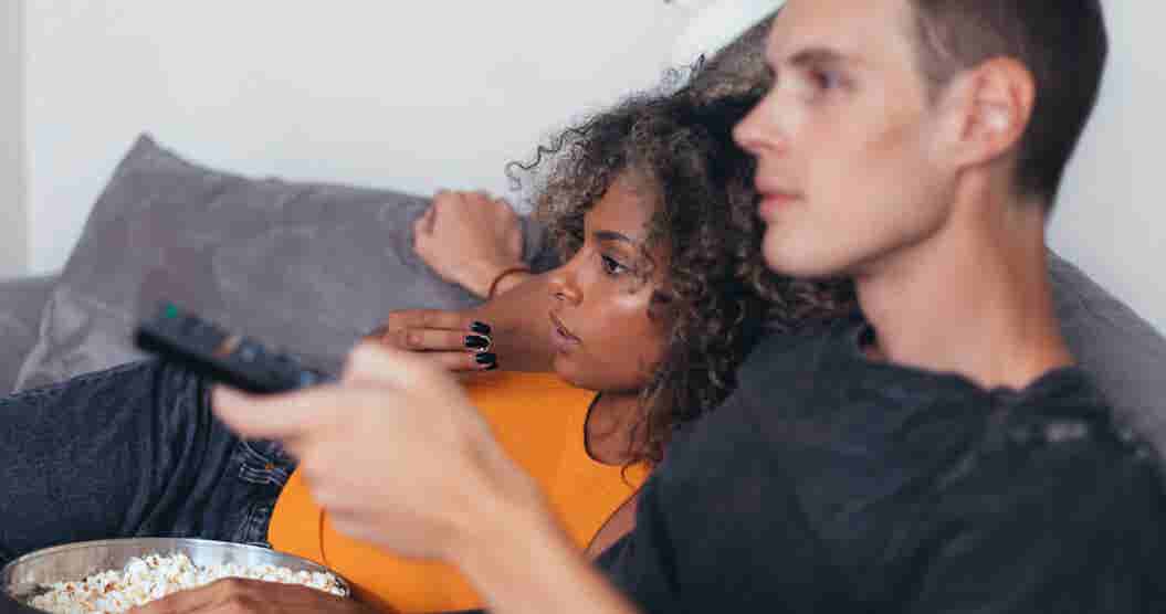 Couple sitting on a couch watching a movie.