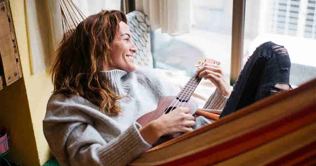 Woman playing a mandolin while looking out a window