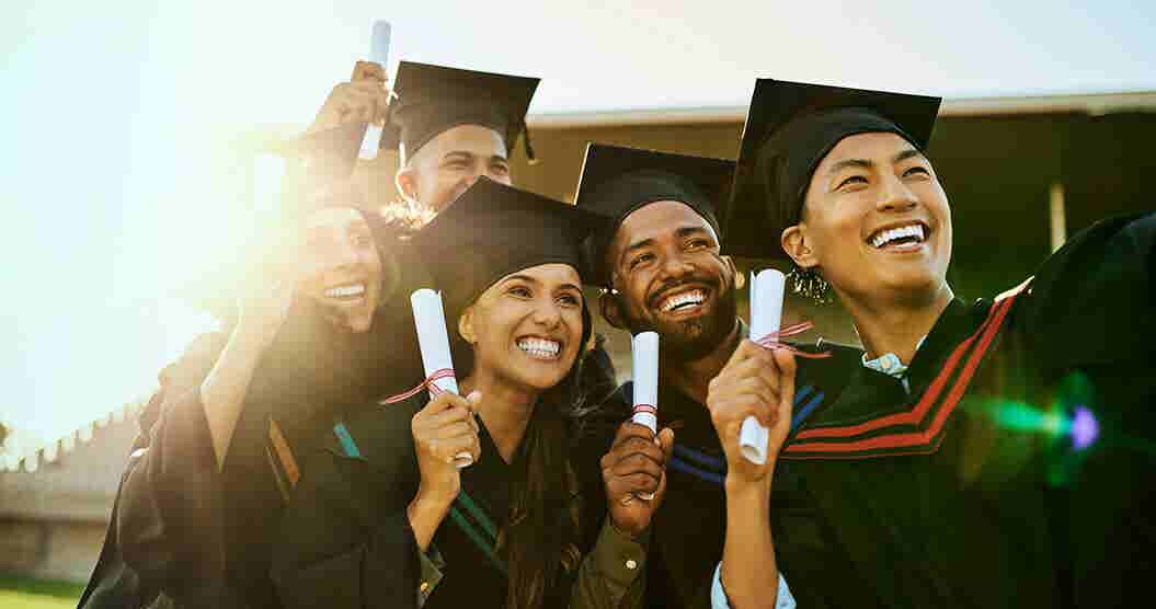 students celebrating graduation while wearing caps and gowns