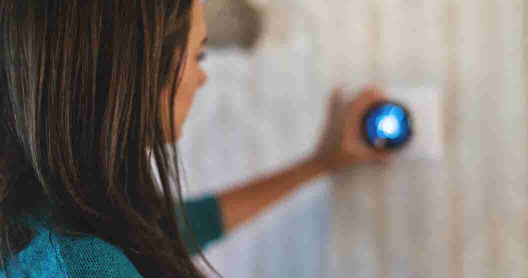 Woman turning down her thermostat to save money on utility bills