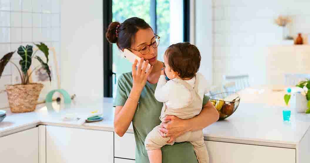 Mother speaking on phone while holding daughter