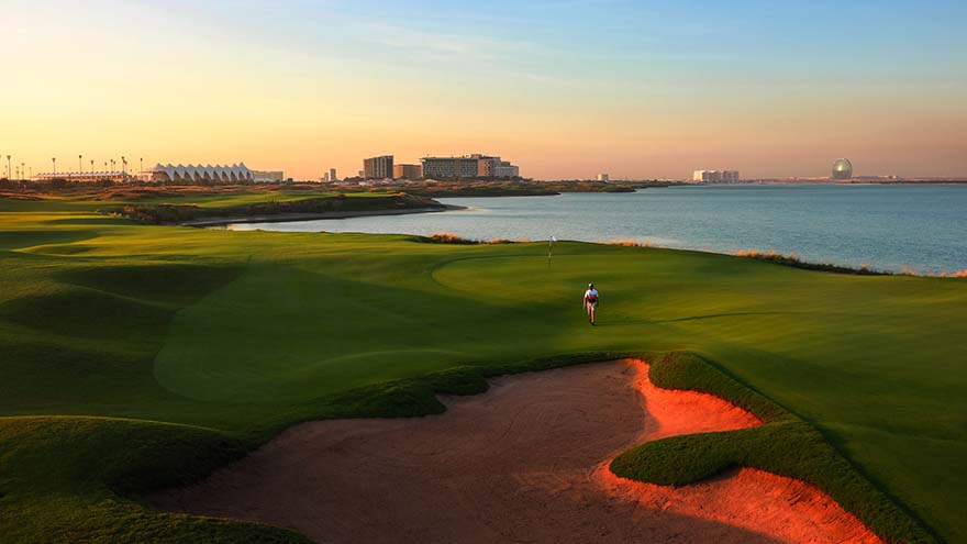 fairway and green at Yas Links with red bunkers and the sea to the right.