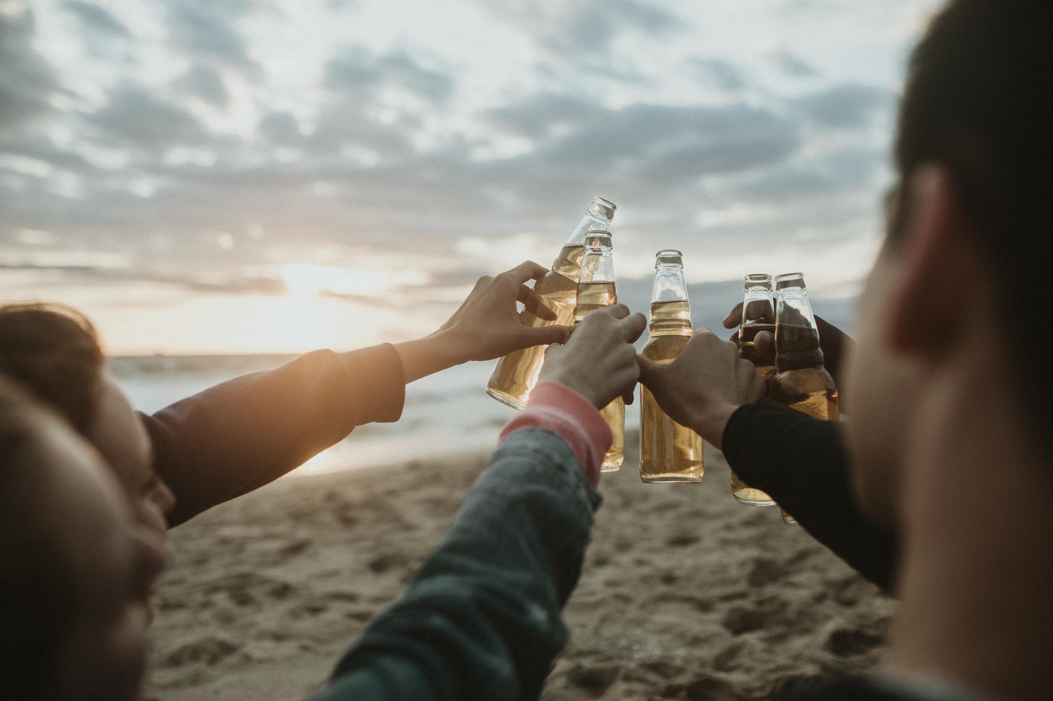 Bottled beers clinking on a beach