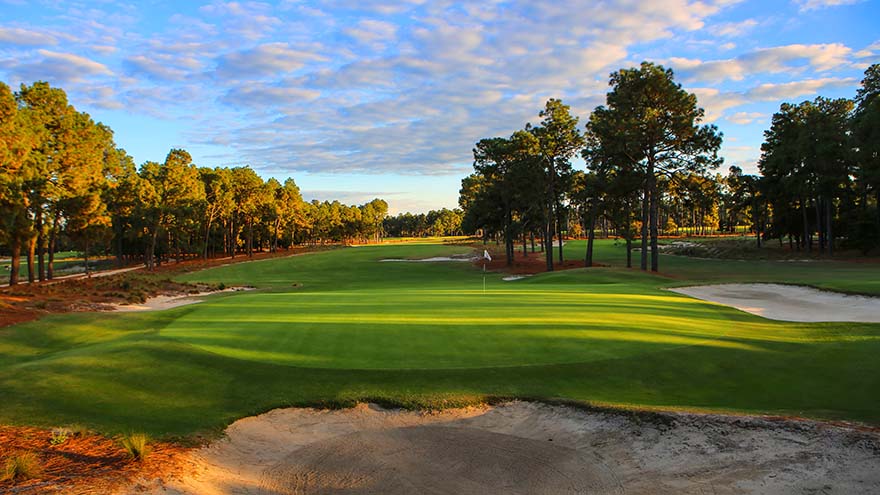 The green and flag at Pinehurst in North Carolina. The fairways are lined by trees as you approach the green.