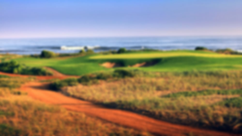 Orange sand with lush green fairways and greens, overlooking the sea.