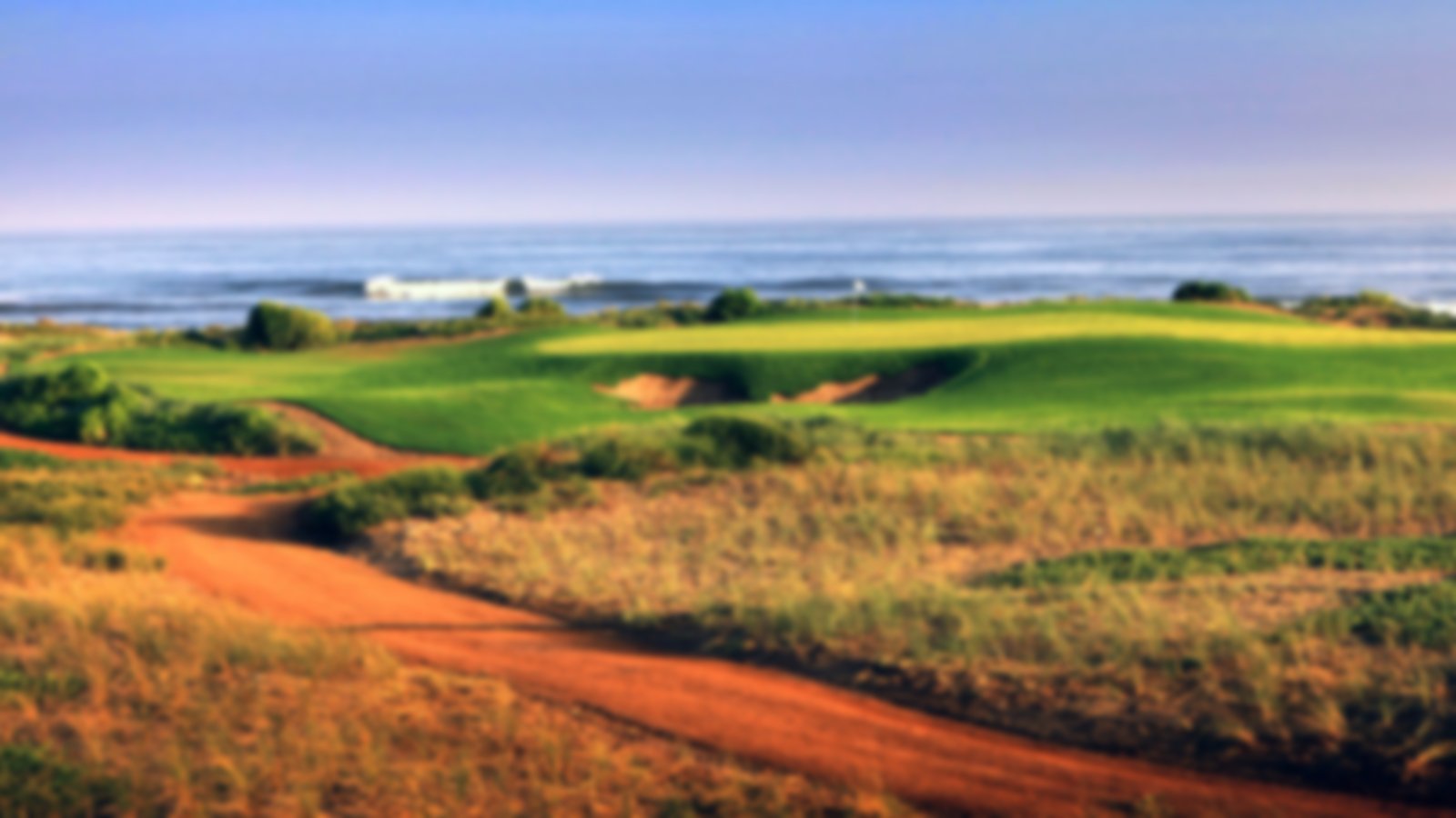 Orange sand with lush green fairways and greens, overlooking the sea.