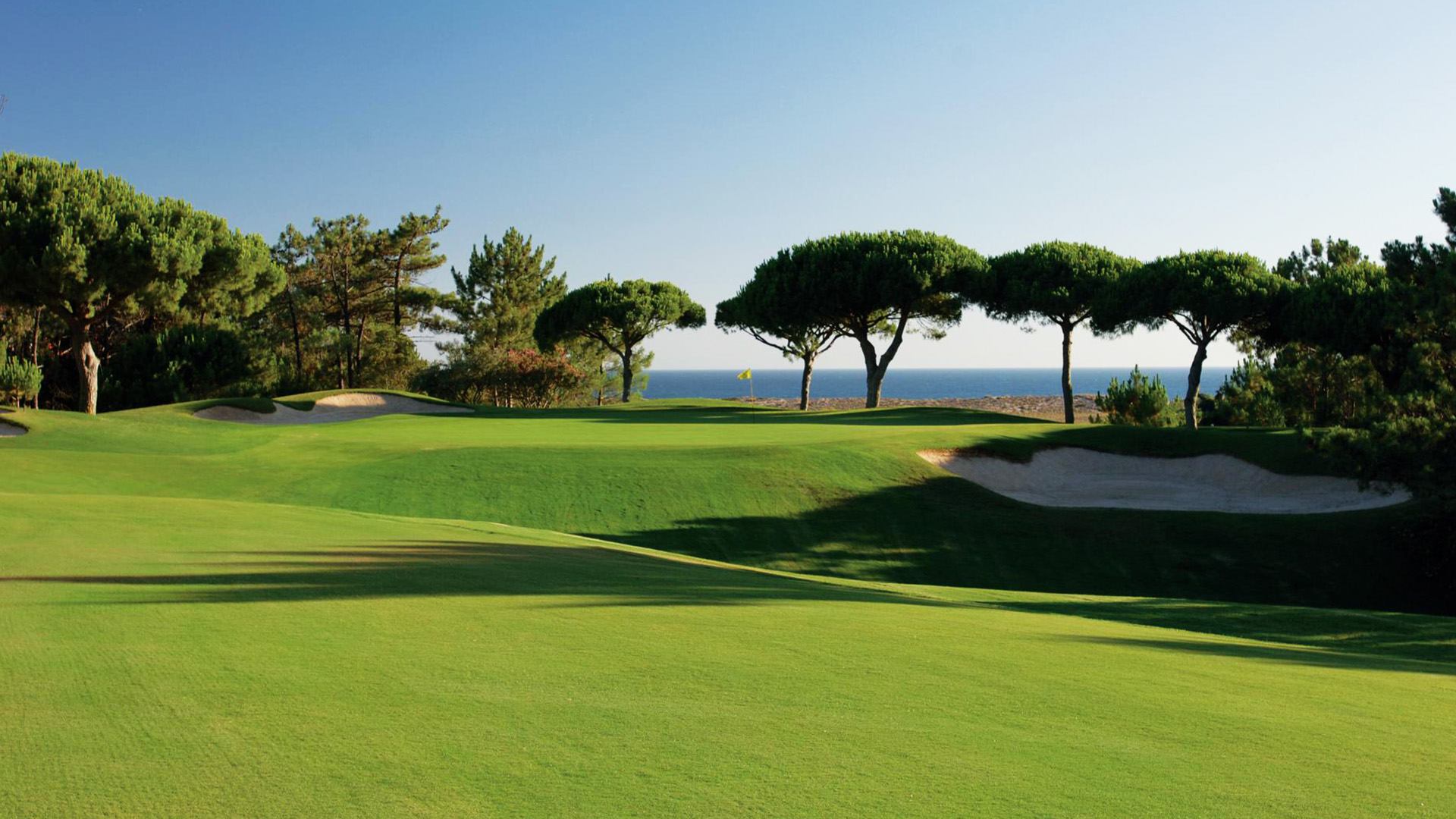Undulating fairways in the shadows with blue skies above