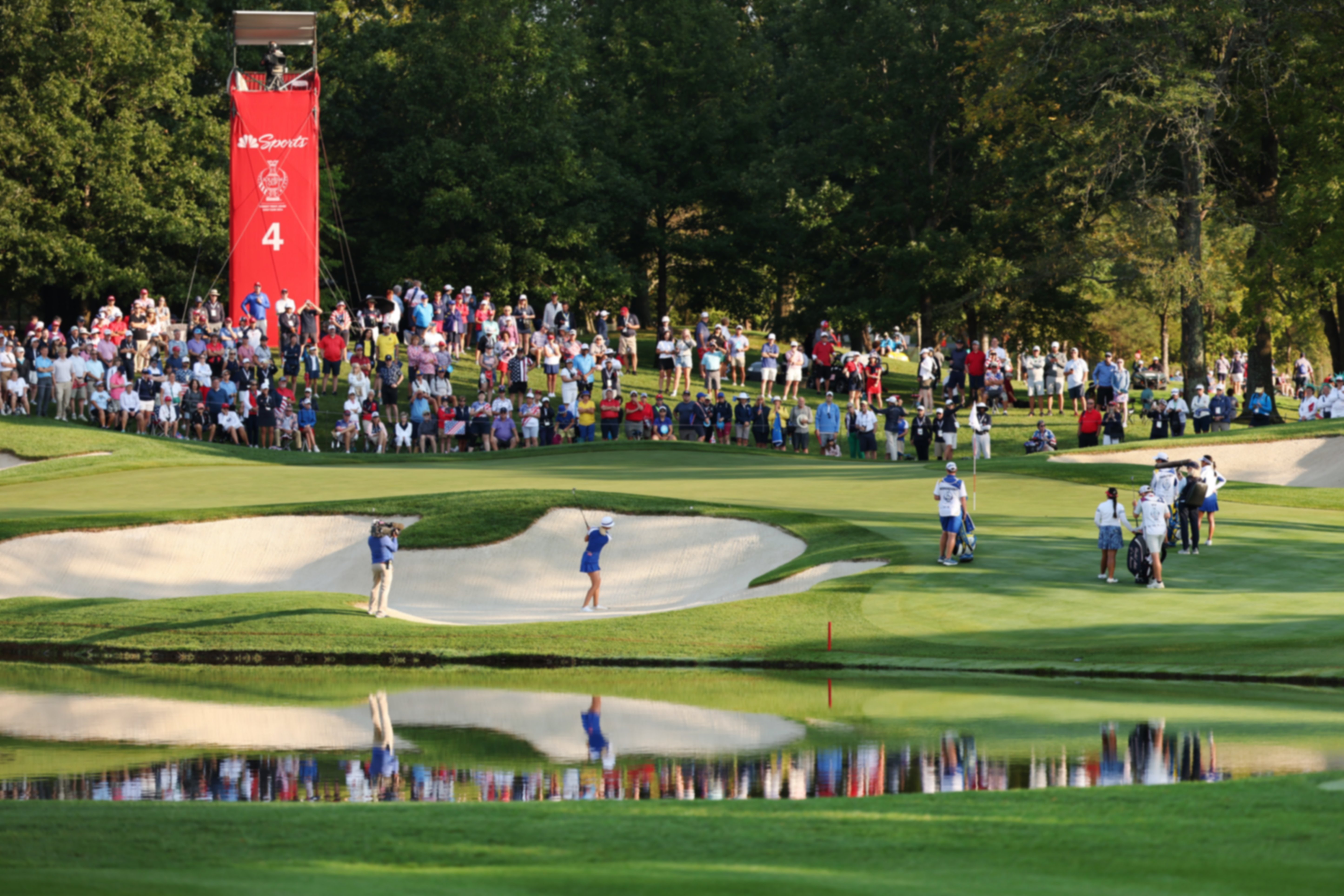 European player hitting from a green side bunker on the 4th hole at Robert Trent Jones course at the Solheim Cup whilst fans watch