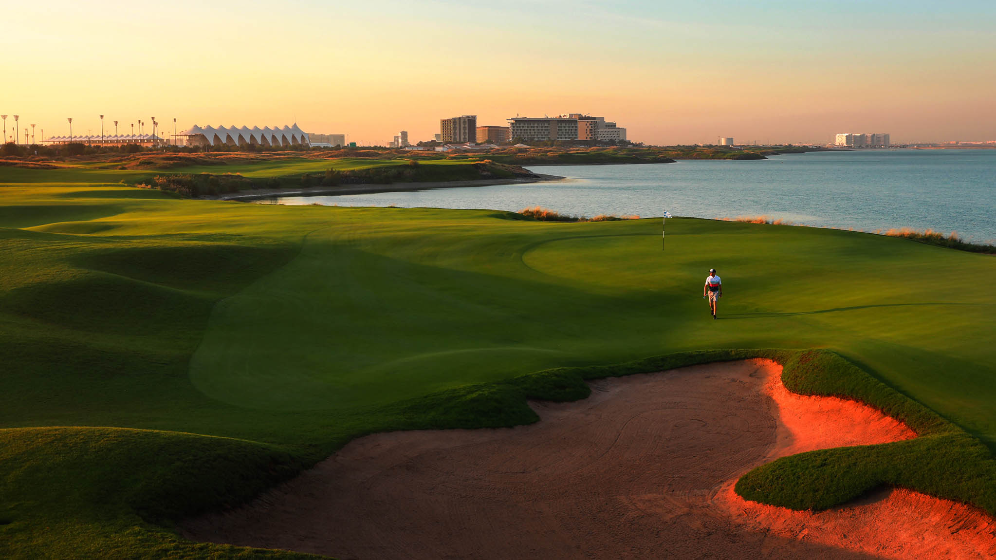 fairway and green at Yas Links with red bunkers and the sea to the right.