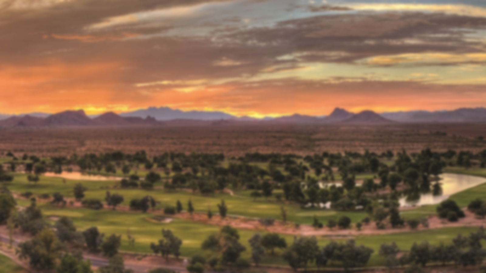 Aerial view of the beautiufl sunset acting as the backdrop at Talking Stick Golf Course. Scottsdale mountains line the horizon.