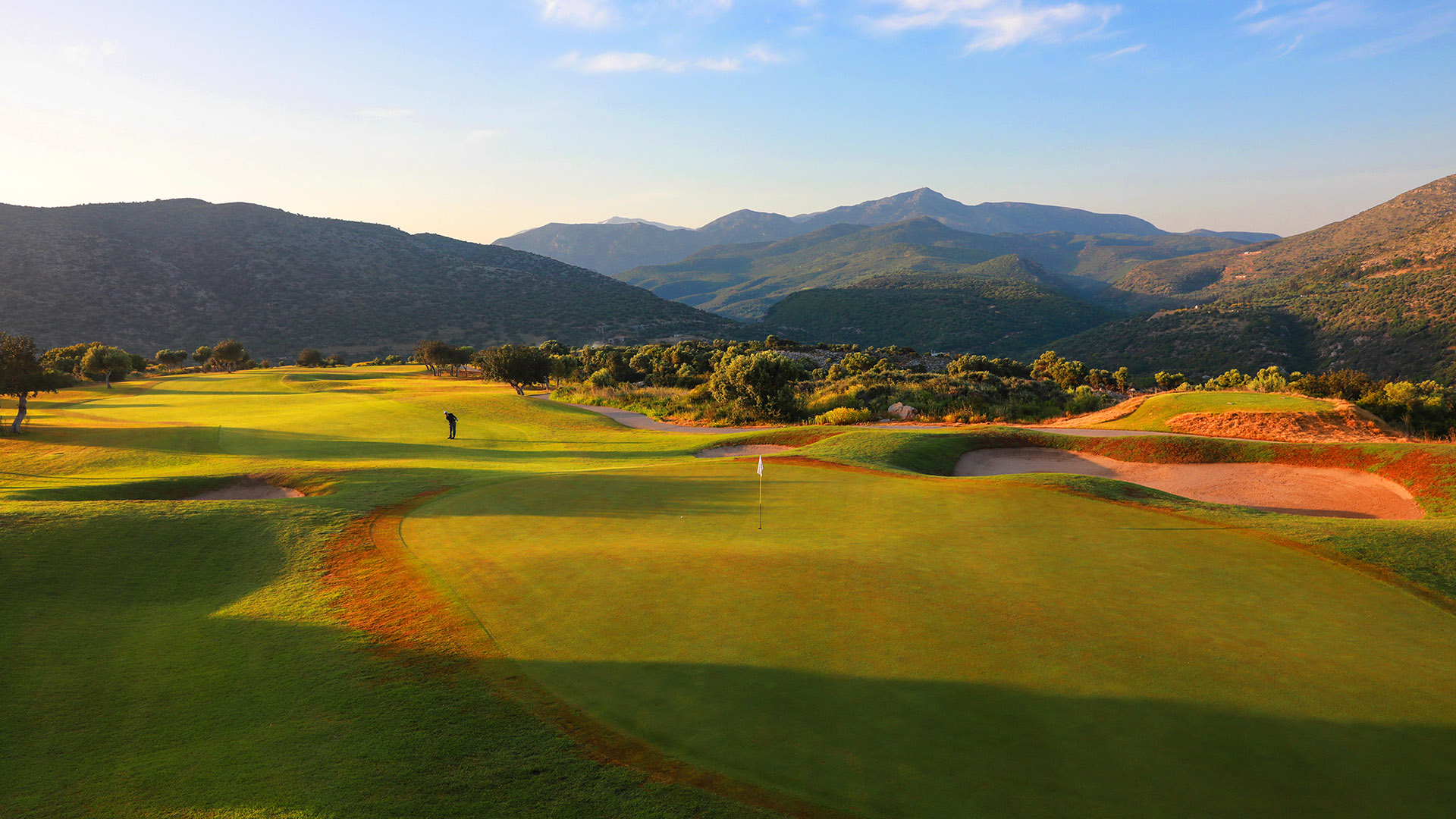 Crete Golf Club green with a beautiful sunset over the backdrop of the surrounding mountains.