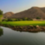 Water in front of the green with the mountains in the backdrop.