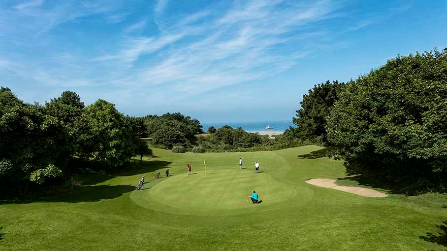 Large green played by a four-ball with blue skies