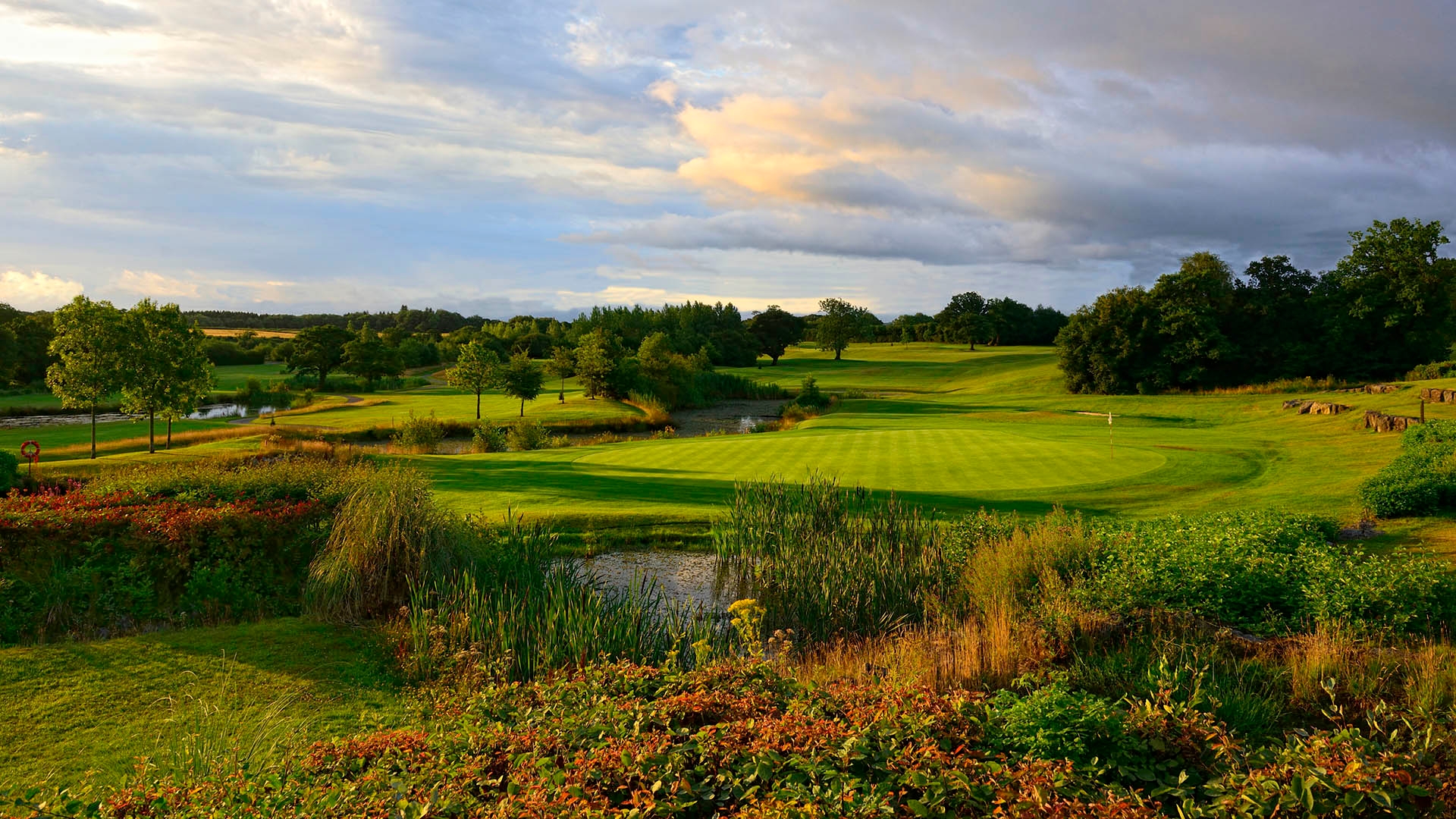 Manicured green at The Vale Resort fronted by water.