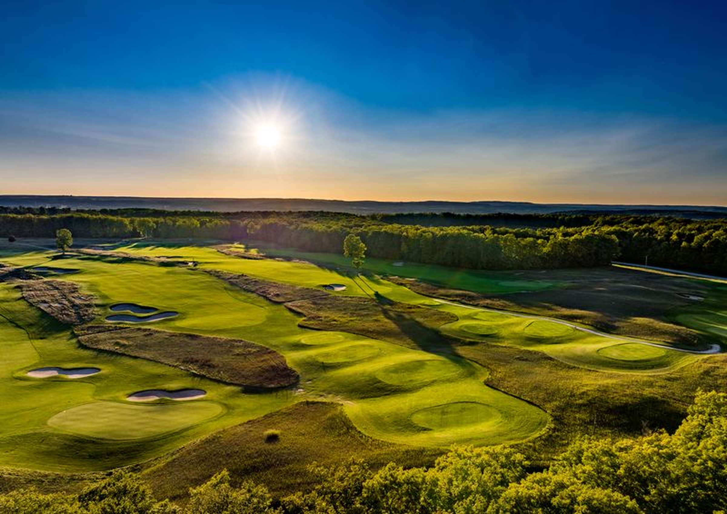 Expansive fairway at Smith Tradition with bunkers under a bright sunrise.