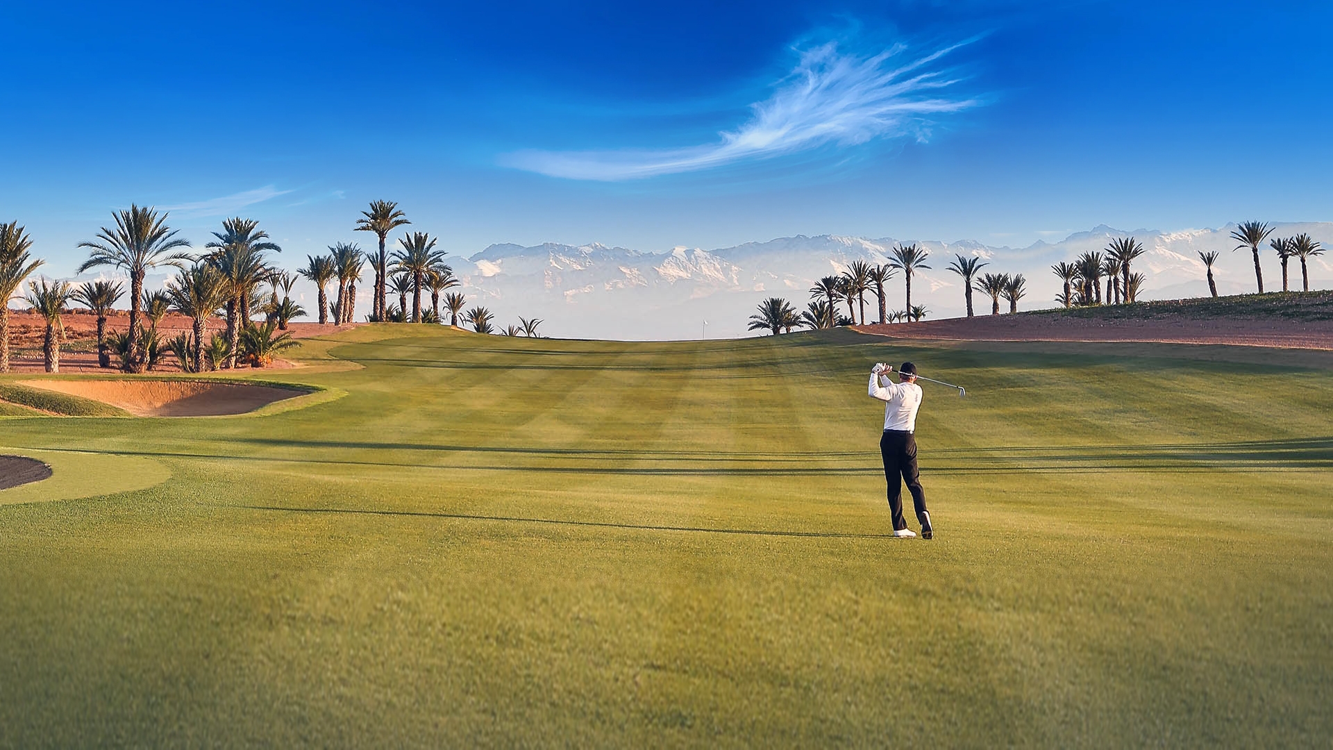 Golfer playing on the beautiful fairway at Assoufid, hitting their approach shot into the mountain backdrop