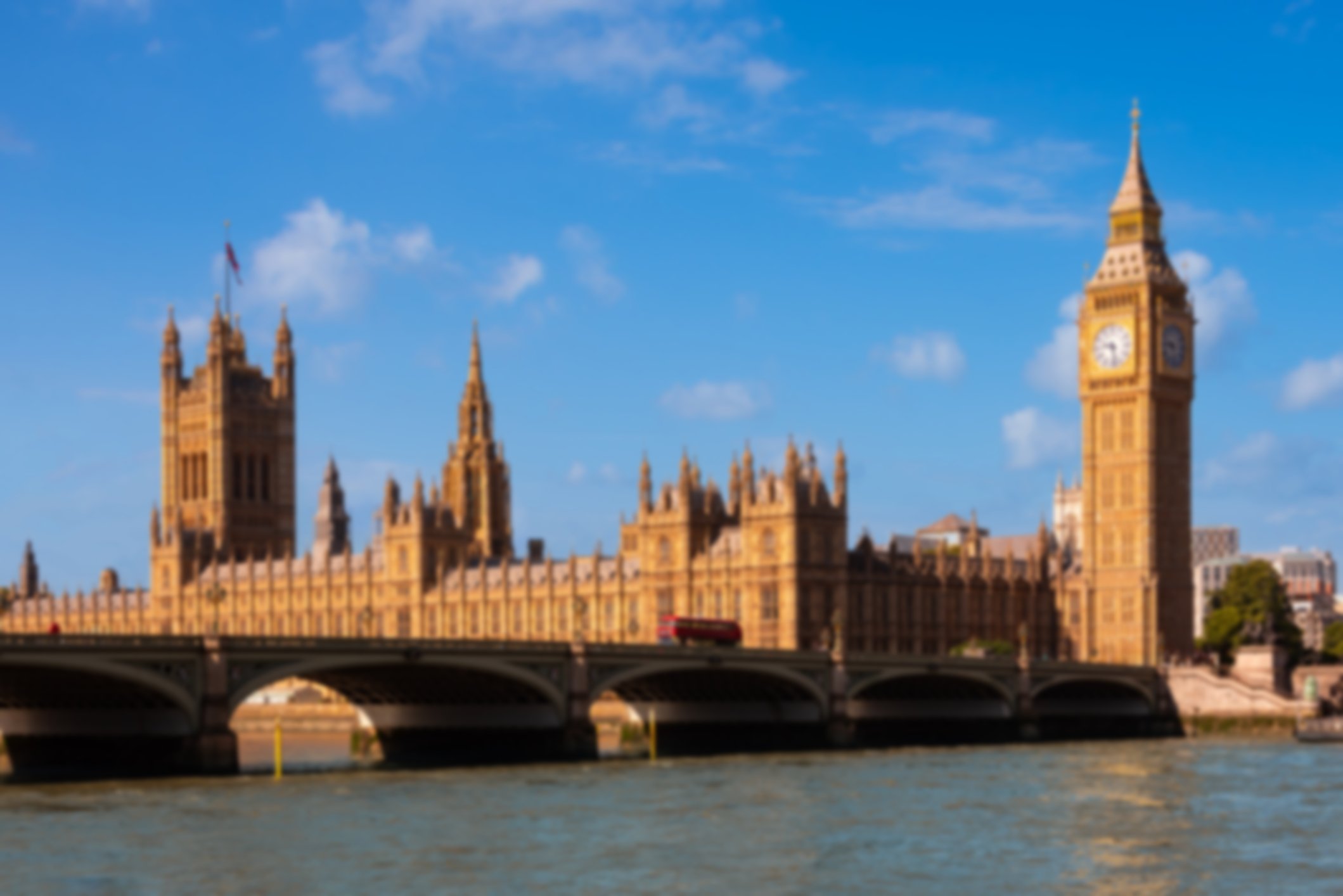 Houses of parliament and Big Ben with a bus driving over the bridge in front