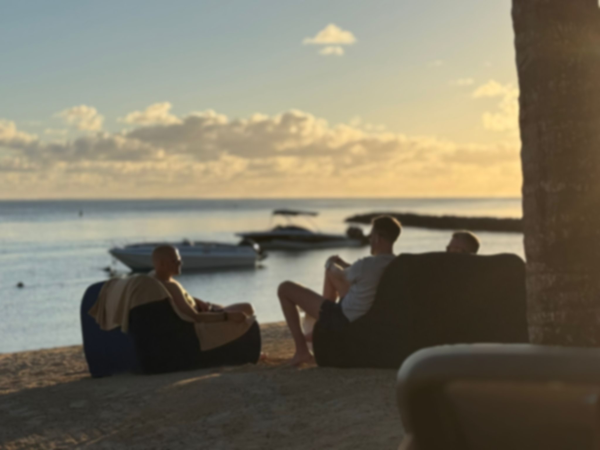 3 men sat on a beach at sunset in Mauritius