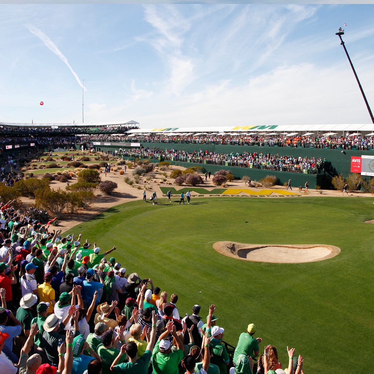 Golfers are cheered on by supporters as they approach the green