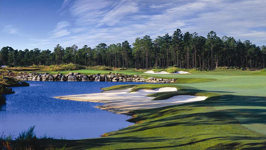 Tree-lined background with bunkers and a water hazard on the left of the hole.