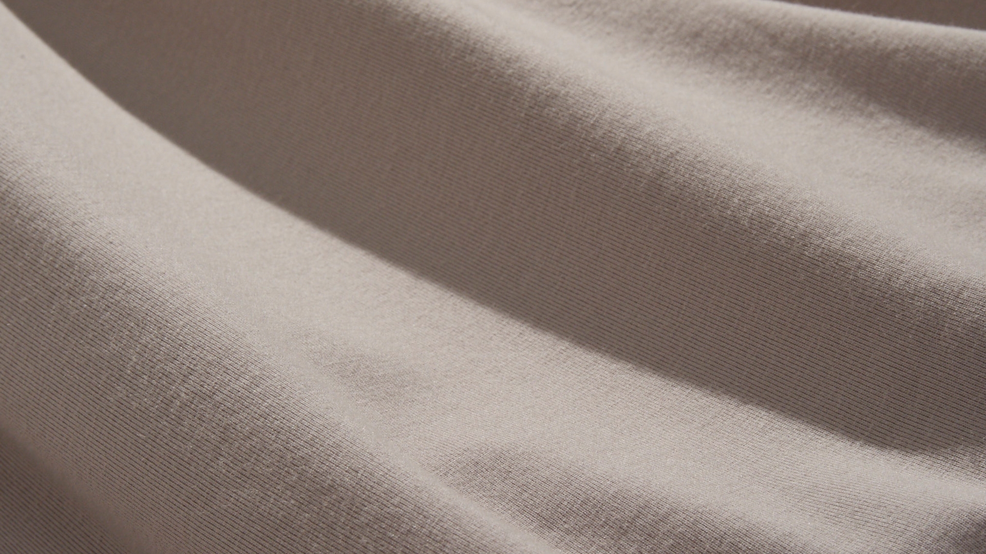 Close-up image of a light and breathable off-white knit fabric.