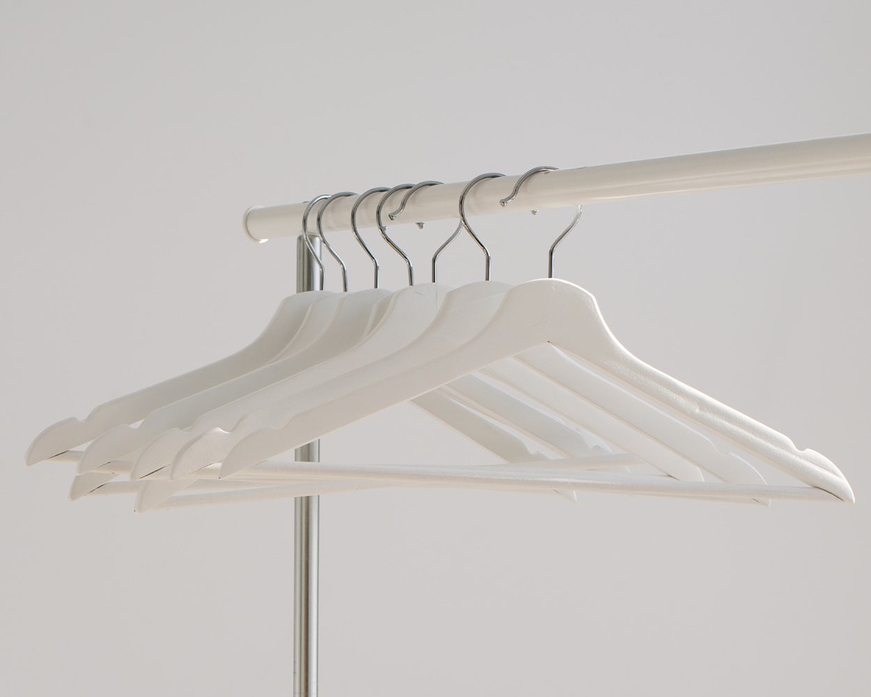  Empty white hangers hanging on a clothing rack.